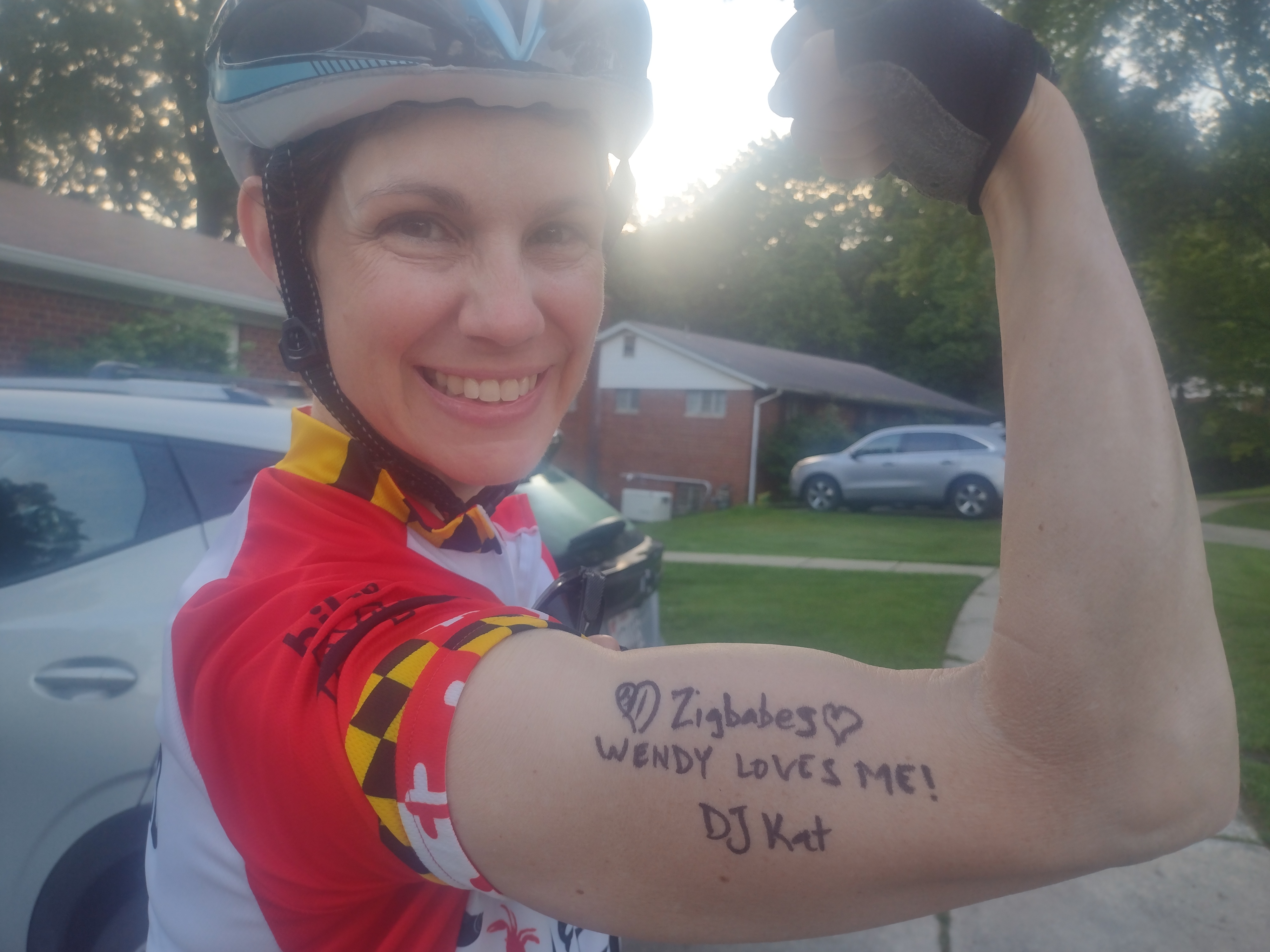 Woman with her arm flexed and the words Zigbabes, Wendy Loves Me, and DJ Kat written on the biceps