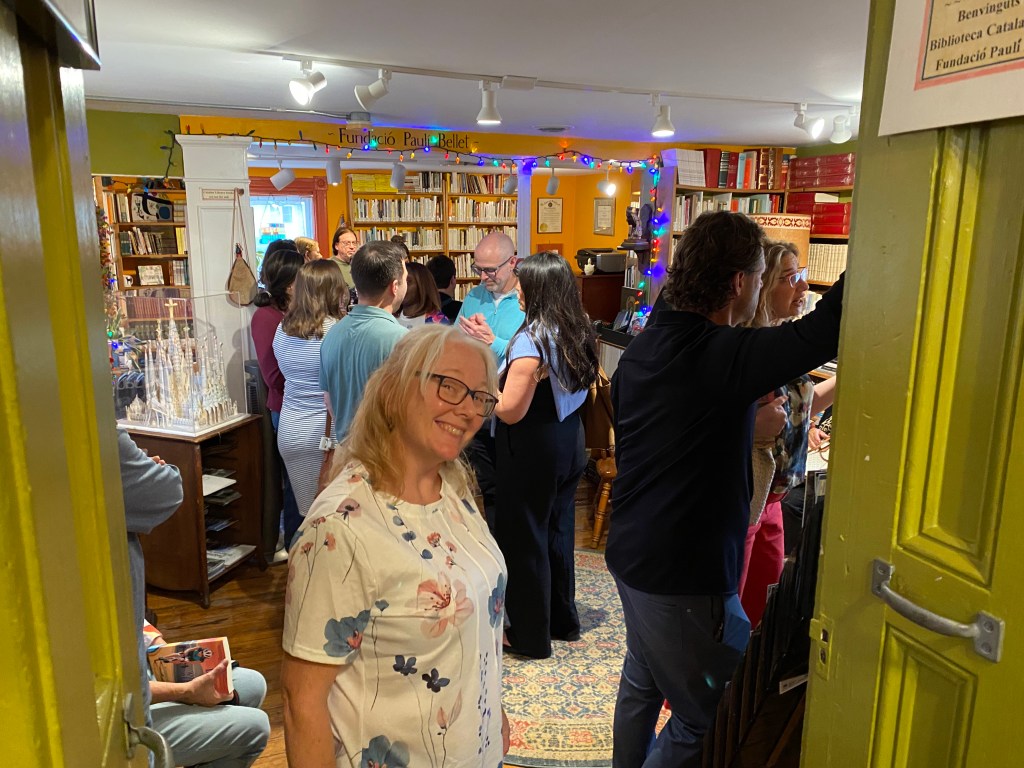 A woman with blond hair and a white shirt smiling for the camera with a crowd behind her