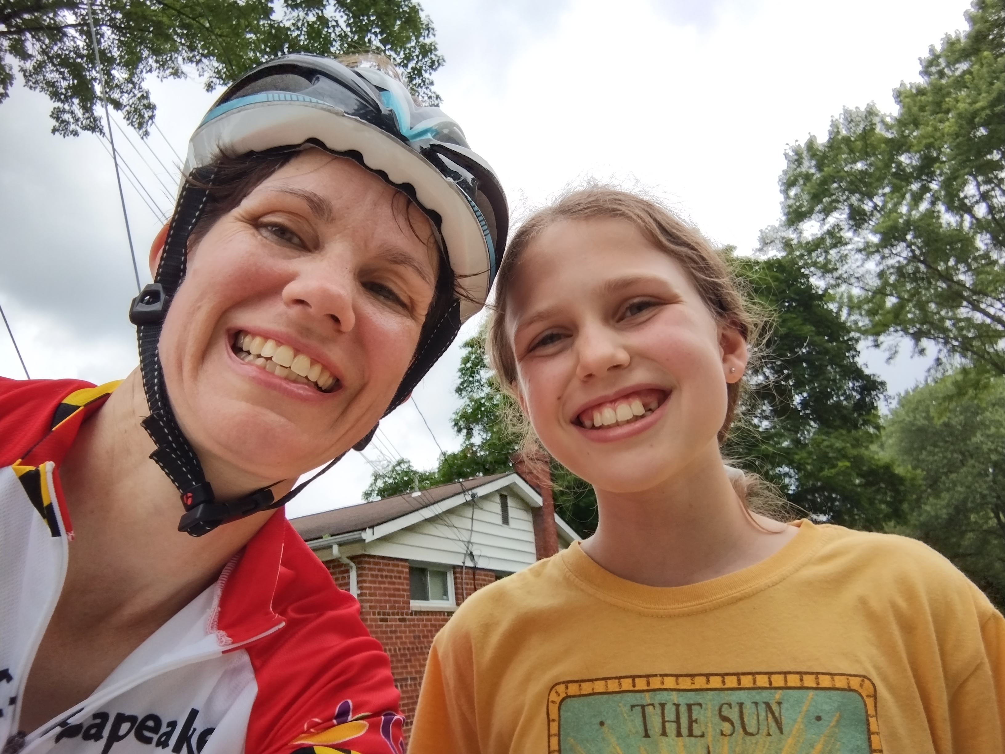A woman and a young girl smiling. The woman is wearing a bike helmet