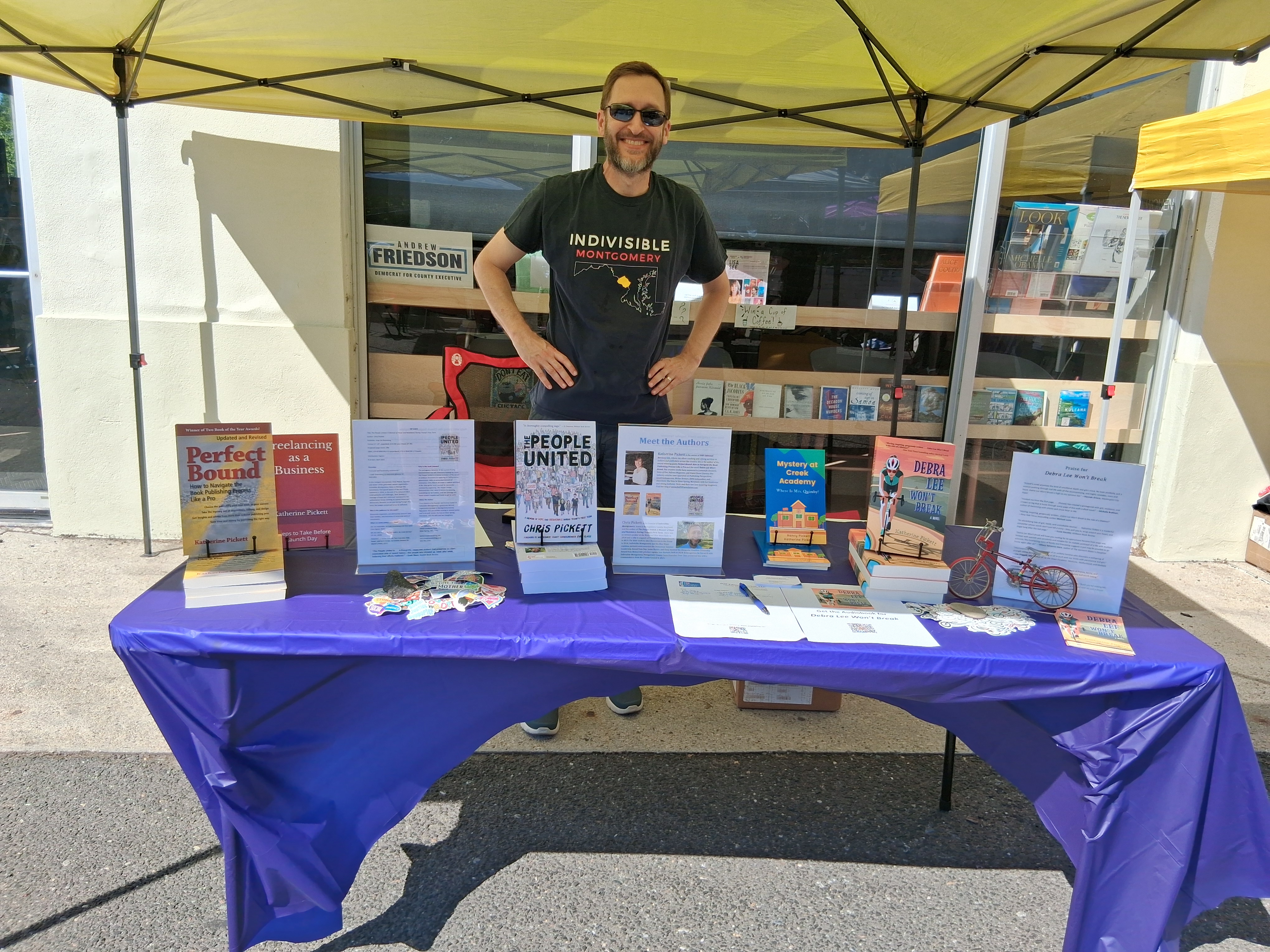 Chris Pickett standing behind a table displaying books published by Hop On Publishing